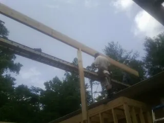 Carpenter setting a ridge beam over a new addition frame — Ice Dam Removal by Roofing Brothers in Tilton