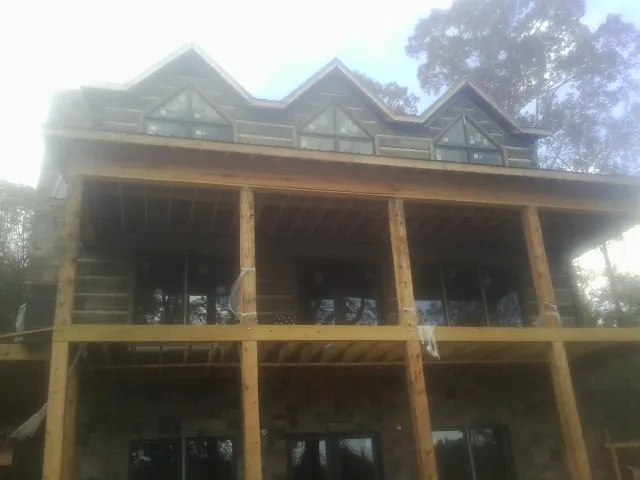 Dormers and porch framing on a large log home under construction — Roof Coating work by our crew in Tilton