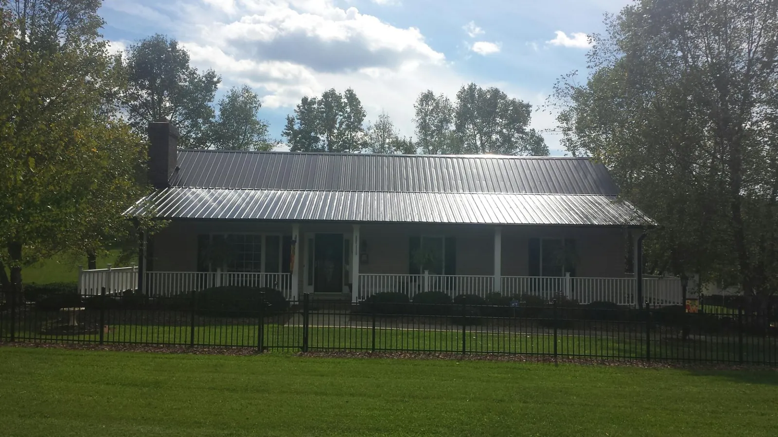 Gray metal roof on a brick ranch with a full width front porch — Gutter Guard Installation work by our crew in Tilton