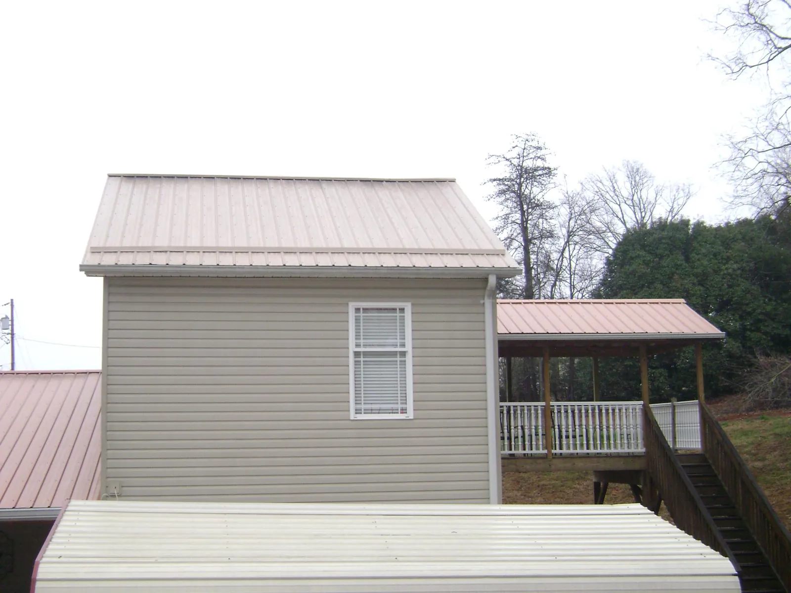 Tan metal roofs on a two story addition and attached porch, from a Roof Replacement job in Tilton