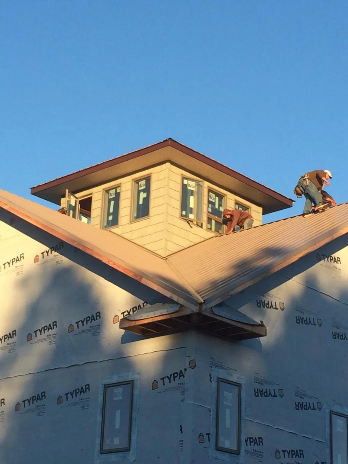 Roofers working around a rooftop cupola on a new metal roof at sunset — Roof Waterproofing in Tilton by Roofing Brothers